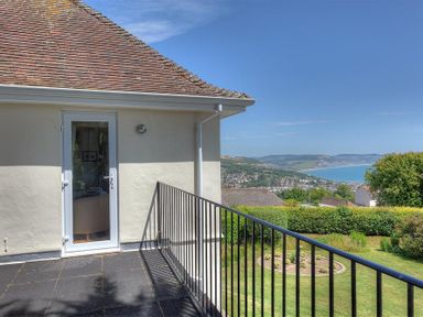A balcony with black metal railing overlooking a garden and a view of the coastline at Somerhill in Lyme Regis