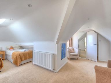 A bedroom with two beds a radiator a chair and a door with a mirror at Somerhill in Lyme Regis