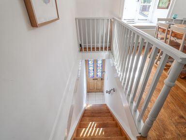 A staircase with wooden steps and white railing next to a wooden door with stained glass panels at Coombe Street Cottage Lyme Regis