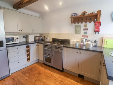 A kitchen with white cabinets a stainless steel oven microwave and toaster at Coombe Street Cottage Lyme Regis