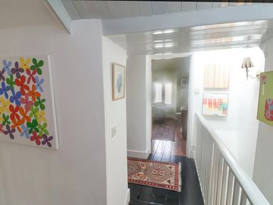 A hallway with a patterned rug on the floor and colorful artwork on the walls at Coombe Street Cottage in Lyme Regis