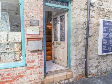 Entrance door with stained glass panels and wooden steps inside at Coombe Street Cottage Lyme Regis