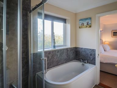 A bathroom with a bathtub and shower at High Cliff Orchard in Lyme Regis
