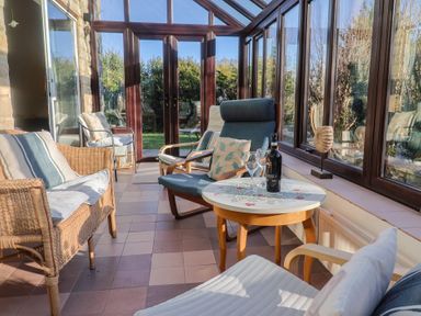 A conservatory with furniture and a wine bottle at High Cliff Orchard in Lyme Regis
