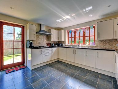 A kitchen with white cabinets black countertop tiled backsplash and floor at 28 Barnes Meadow in Uplyme