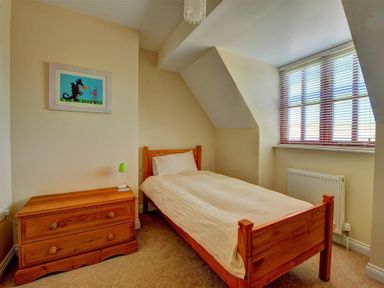 A bedroom with a wooden bed and chest of drawers with a green lamp at 28 Barnes Meadow in Uplyme