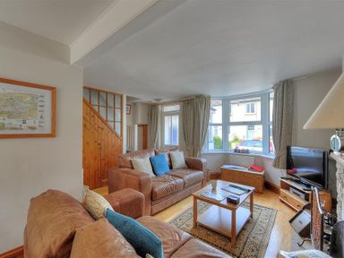 A living room with leather sofas a wooden coffee table a television and a bay window at Ivy Cottage in Beer