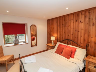 A bedroom with a bed wooden bedside tables and a wicker chair at 3 Home Farm South in Rousdon