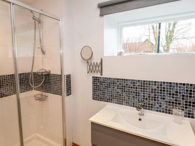 A bathroom with a shower enclosure sink and a window at 3 Home Farm South in Rousdon