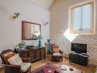 A living room with a sofa, coffee table, and TV at The Stone Barn in Bridport