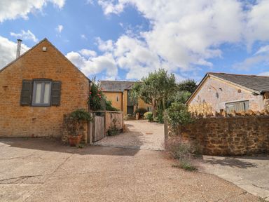 An outdoor view of buildings and trees at The Stone Barn in Bridport