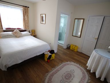 A bedroom with a bed a side table a mirror and a round table with a cloth at Vine Cottage in Charmouth
