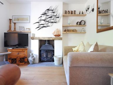 A living room with a wood stove TV wooden shelves and sofa at Bethel Cottage in Lyme Regis