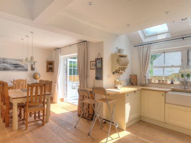 A kitchen and dining area with wooden chairs and table bar stools by counter at Bethel Cottage Lyme Regis