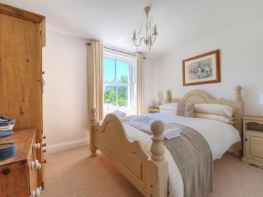 A bedroom with a wooden bed and dresser near a window at Bethel Cottage in Lyme Regis