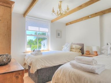 A bedroom with two single beds wooden beams on the ceiling and a wooden dresser at Bethel Cottage in Lyme Regis