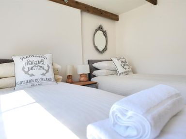 A bedroom with two single beds white bedding pillows bedside table lamps and a wall mirror at Bethel Cottage in Lyme Regis