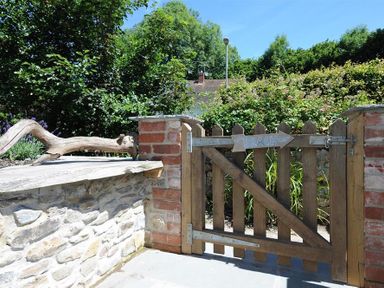 A wooden gate with a beach sign surrounded by stone and brick walls at Bethel Cottage in Lyme Regis
