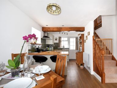 A kitchen and dining area with wooden furniture a staircase and kitchen appliances at Sunnyside in Colyton