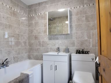 A bathroom with a bathtub sink unit toilet and a mirror cabinet at Sunnyside in Colyton