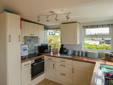 A kitchen with cupboards, a microwave, kettle, toaster, and window with a view at Ammonite in Lyme Regis