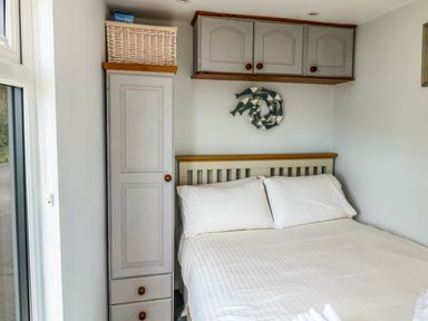 A bedroom with a bed with white pillows and a cupboard with cabinets above at Ammonite in Lyme Regis