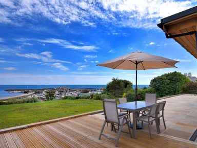 An outdoor patio with table chairs and umbrella overlooking a marina and sea at Harbour Heights Cottage in Lyme Regis