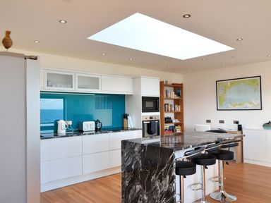 A modern kitchen with a marble island and four stools at Harbour Heights Cottage Lyme Regis