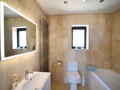 A bathroom with a sink and mirror toilet bathtub and towel on the tub at Harbour Heights Cottage in Lyme Regis