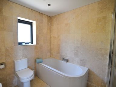 A bathroom with a bathtub a toilet and a window at Harbour Heights Cottage in Lyme Regis