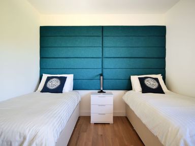 A bedroom with two single beds separated by a white nightstand with a black lamp at Harbour Heights Cottage Lyme Regis