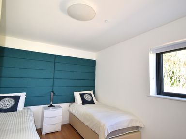 A bedroom with two single beds and a blue padded headboard at Harbour Heights Cottage Lyme Regis