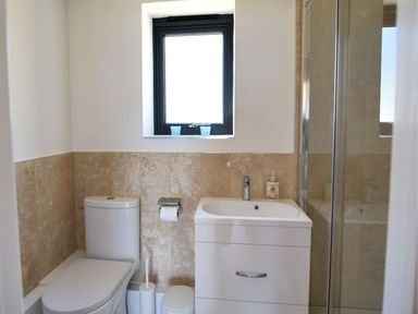 A bathroom with a toilet sink cabinet shower and window at Harbour Heights Cottage in Lyme Regis