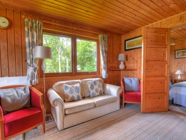 A living room with a sofa and armchairs by windows with curtains and a floor lamp at 4 Pinewood Retreat in Pinewood