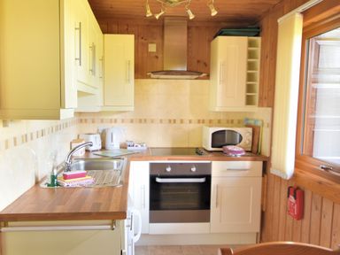A kitchen with white cabinets wooden countertops an oven microwave sink and window at 4 Pinewood Retreat in Pinewood