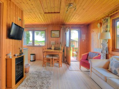 A living room with a dining table chairs sofa and a television at 4 Pinewood Retreat in Pinewood
