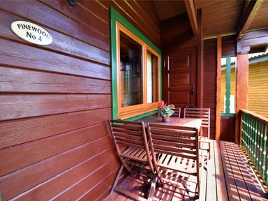 A wooden porch with a table and four chairs and a flower pot on the table at 4 Pinewood Retreat in Pinewood
