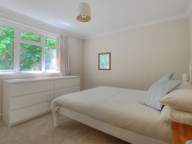 A bedroom with a bed pillows a dresser window and a wall mirror at 36 Fernhill Heights in Charmouth