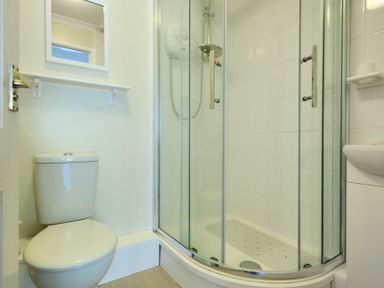 A bathroom with a toilet and a corner shower with glass doors at 36 Fernhill Heights in Charmouth