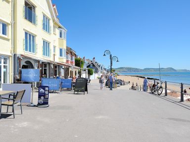 A beachfront promenade with a restaurant and people walking near the sea at Seashore in Lyme Regis