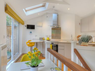 A kitchen with yellow chairs and flowers on a table at Seashore in Lyme Regis