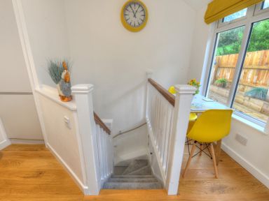 A stairway with white railings next to a table with yellow chairs and a window showing a wooden fence at Seashore in Lyme Regis