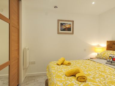 A bedroom with a bed covered in yellow floral bedding and yellow towels on top at Seashore in Lyme Regis