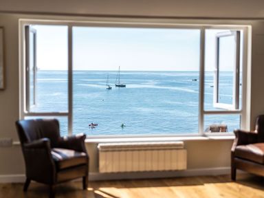 A room with two chairs facing a window overlooking the sea with boats at 3 Beach Way House Lyme Regis