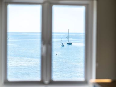 A view of two sailboats on the water through a window at 3 Beach Way House in Lyme Regis