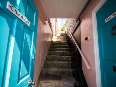 Stone steps between two buildings with blue doors on either side at 3 Beach Way House in Lyme Regis
