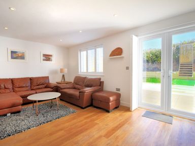 A living room with brown leather sofas a round coffee table a lamp and large glass doors at Shire View in Lyme Regis