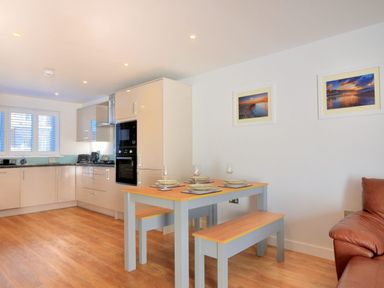 A kitchen with dining table set for four and two framed pictures on the wall at Shire View in Lyme Regis