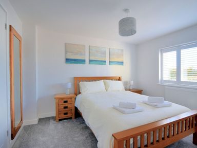 A bedroom with a double bed and wooden furniture with paintings above the bed at Shire View in Lyme Regis
