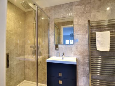 A bathroom with a glass shower enclosure sink with cabinet mirror and towel rack at Shire View in Lyme Regis